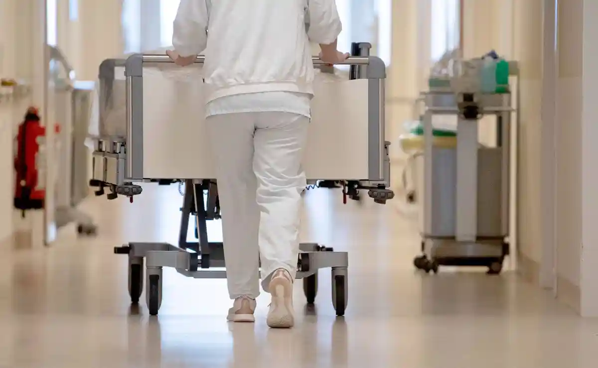 Больница:Медсестра толкает больничную кровать по коридору.