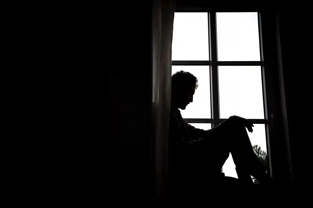 Депрессия:Мужчина сидит перед окном.