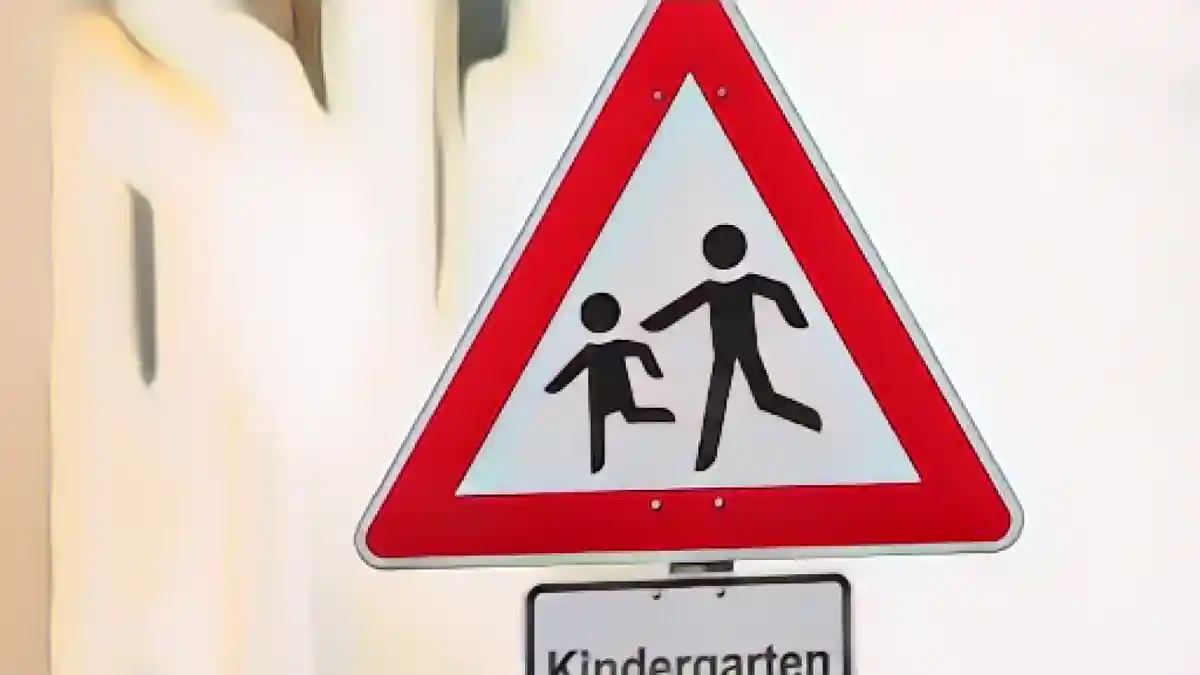 Дорожный знак с надписью "Детский сад" стоит перед детским садом.:Дорожный знак с надписью "Детский сад" перед детским садом. Фото