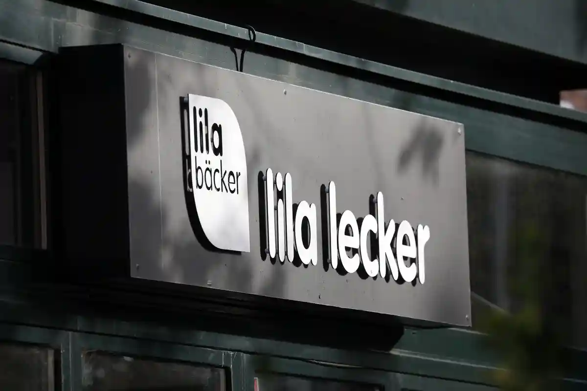 Фиолетовый пекарь:Логотип компании Lila Bäcker с надписью "lila lecker" на ветке в балтийском морском курорте.