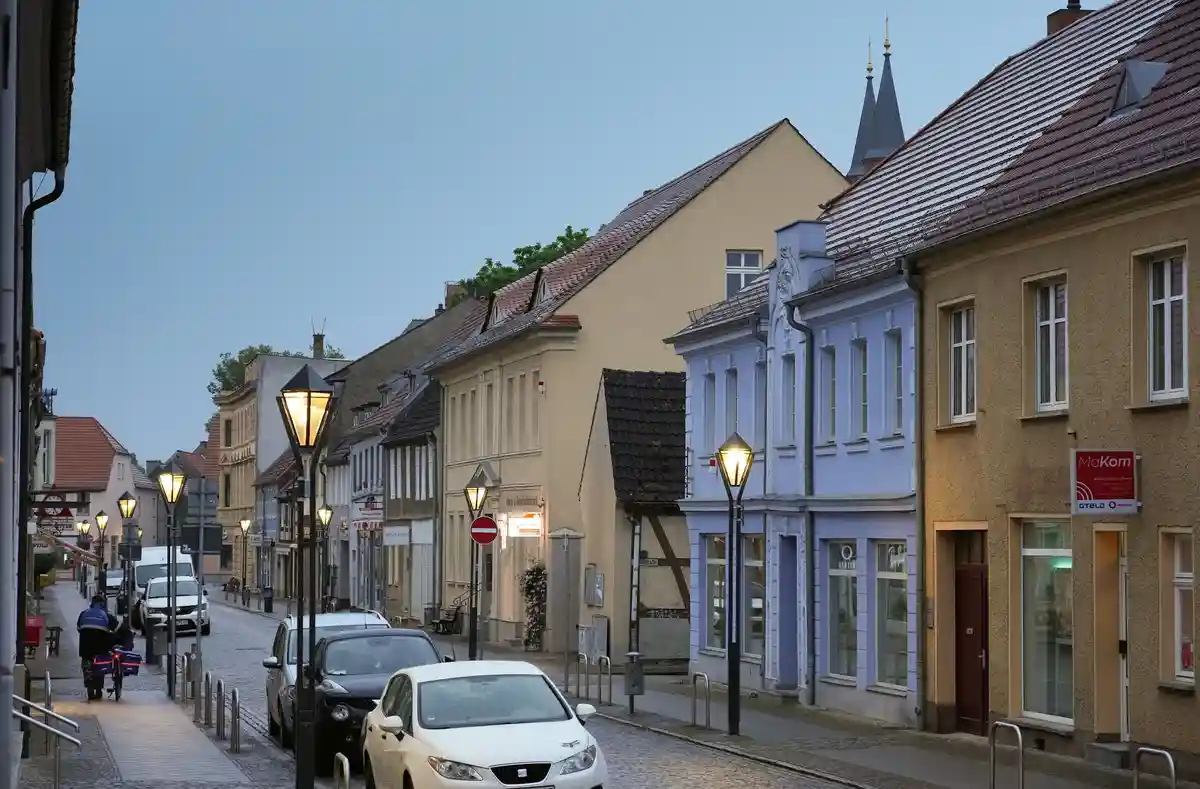Исторический старый город Кириц:Разносчик газет толкает свой велосипед по пешеходной дорожке в сторону рыночной площади ранним утром.