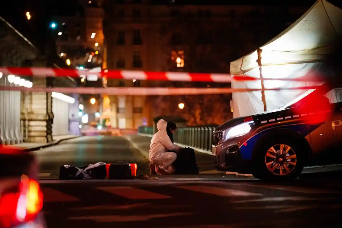 Криминалистика:Сотрудник отдела уголовного розыска работает на месте преступления возле Эйфелевой башни в Париже.