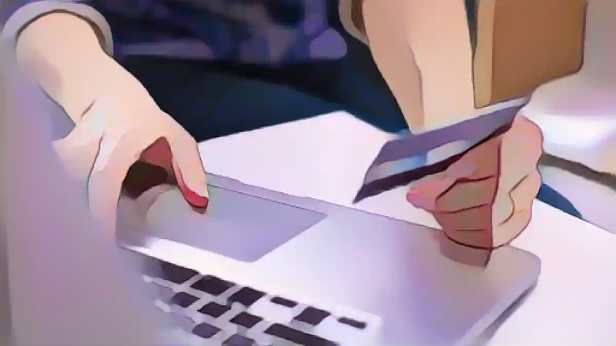 Кто-то держит в руках кредитную карту, чтобы посмотреть на нее во время использования лаптона.:Как использовать вознаграждение по кредитной карте, чтобы меньше тратить на подарки к праздникам