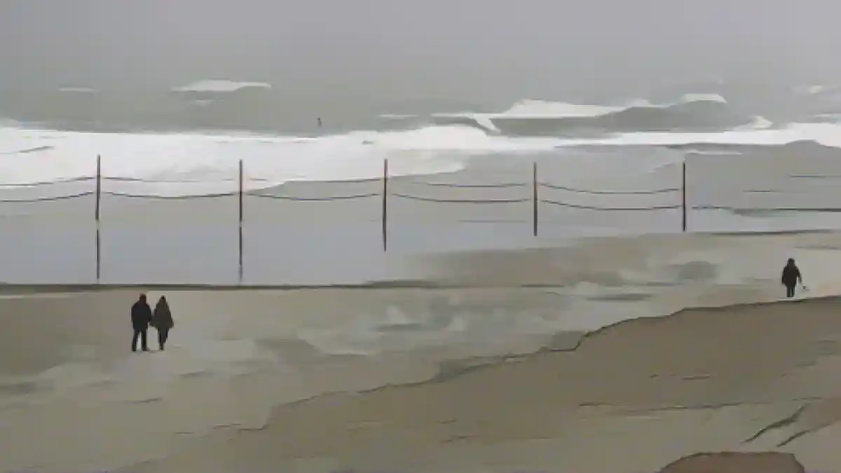 Любители пляжных прогулок борются с сильным ветром на острове Вангерооге.:Любители пляжных прогулок борются с сильным ветром на острове Вангерооге. Фото