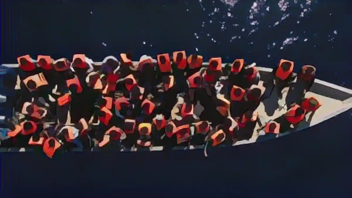 Люди сидят в деревянной лодке в Средиземном море. Символическое изображение:Люди сидят в деревянной лодке в Средиземном море. Символическая фотография