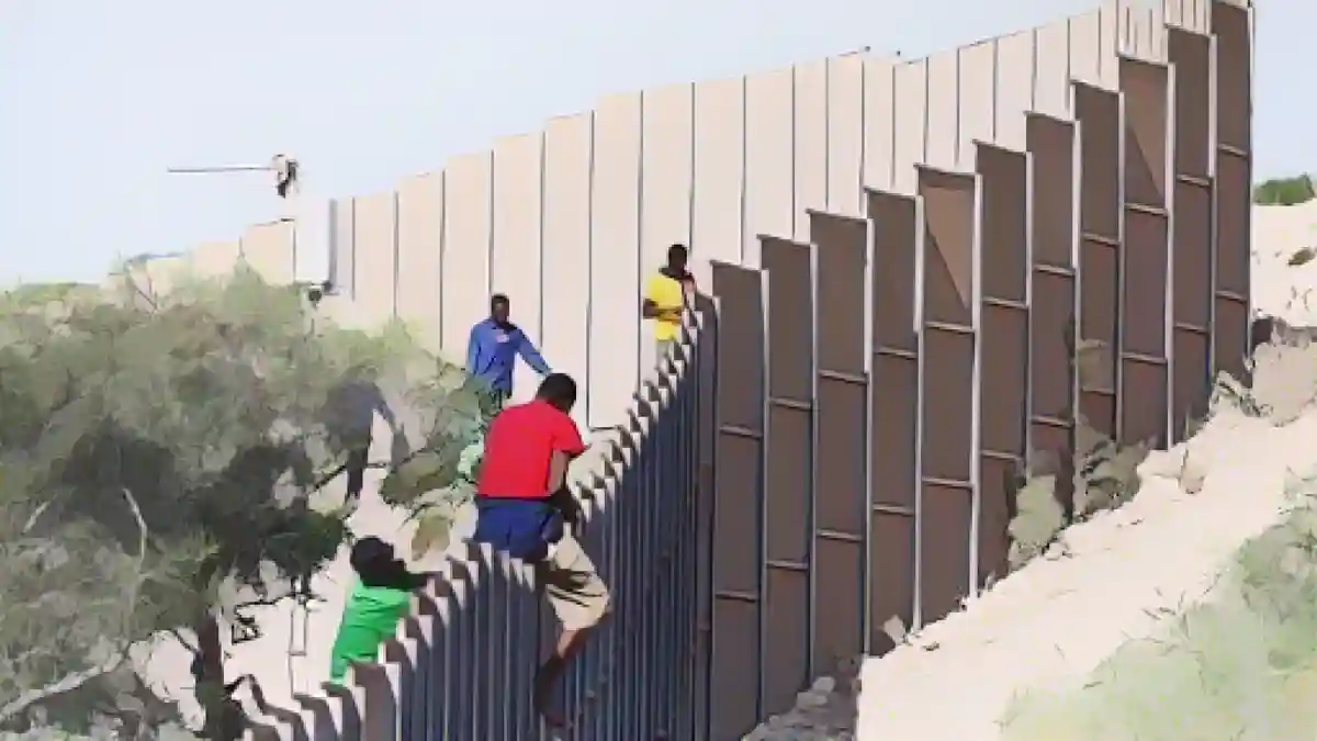 Мигранты перелезают через забор на острове Лампедуза.:Мигранты перелезают через забор на острове Лампедуза. Фото