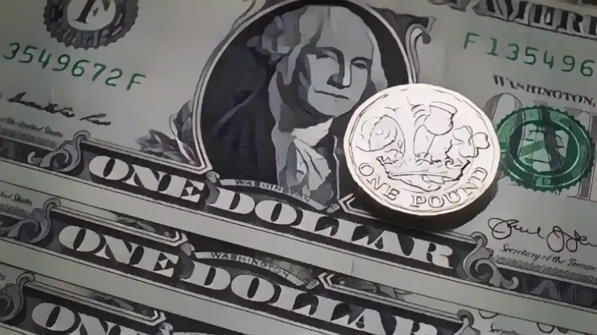 Монета номиналом в 1 фунт стерлингов рядом с долларовыми купюрами 4 апреля 2017 года в Бате, Англия: