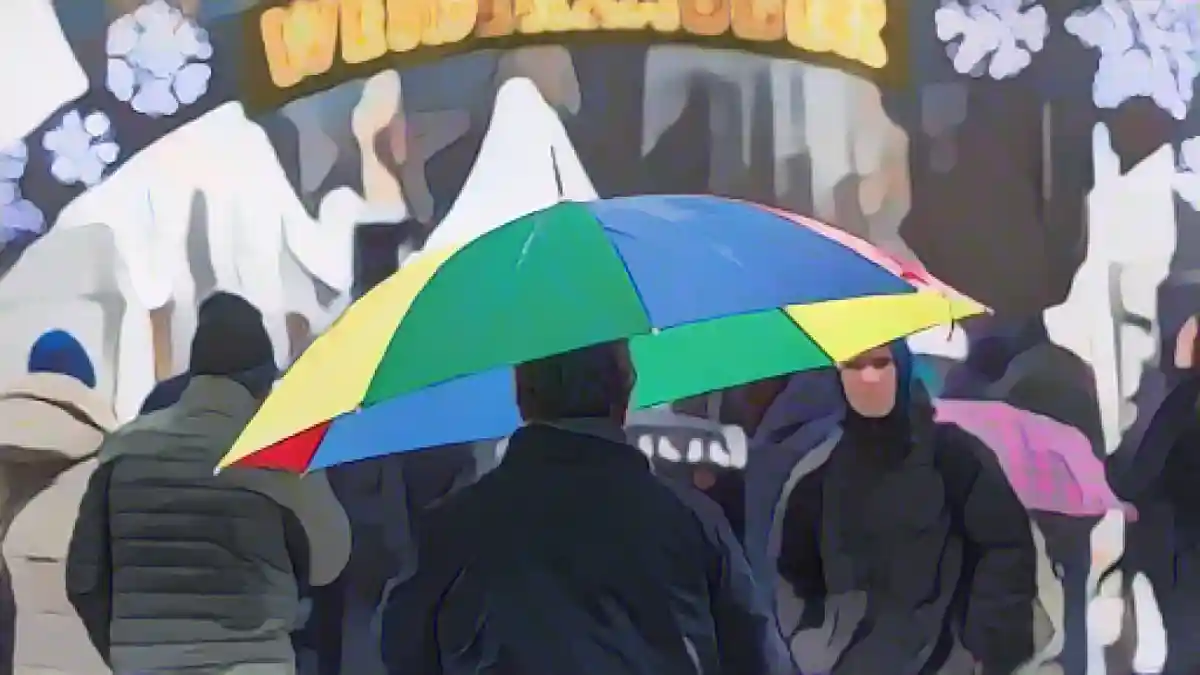 Мужчина идет по рождественскому рынку под моросящим дождем с зонтиком.:Мужчина идет по рождественскому рынку с зонтиком под моросящим дождем. Фото