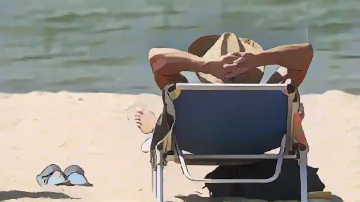 Мужчина лежит в шезлонге на пляже.:Мужчина лежит в шезлонге на пляже. Фото