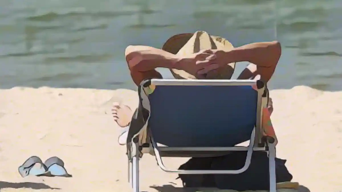 Мужчина лежит в шезлонге на пляже.:Мужчина лежит в шезлонге на пляже. Фото