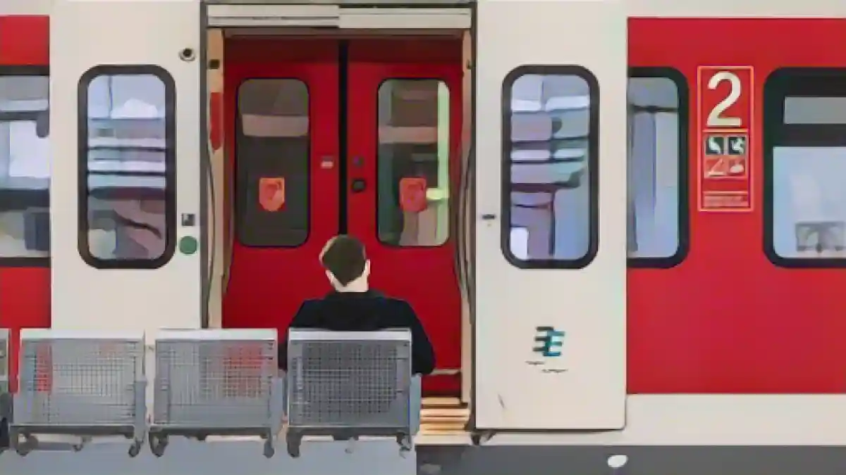 Мужчина сидит на скамейке перед региональным поездом на железнодорожной станции.:Мужчина сидит на скамейке перед региональным поездом на железнодорожной станции. Фото