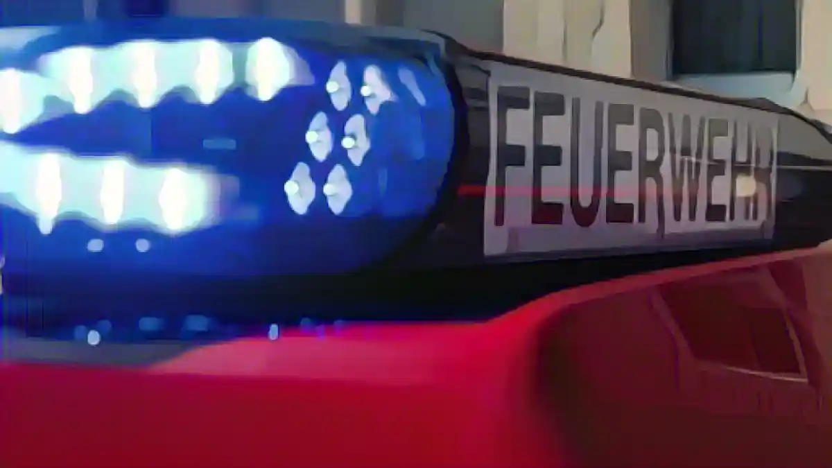 На месте происшествия припаркован автомобиль пожарной бригады с включенными синими огнями.:Автомобиль пожарной службы с включенными синими фарами на месте чрезвычайной ситуации. Фото