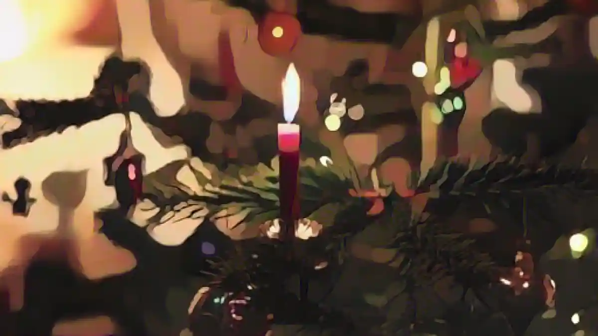 На празднично украшенной рождественской елке горит свеча.:Свеча горит на празднично украшенной рождественской елке. Фото