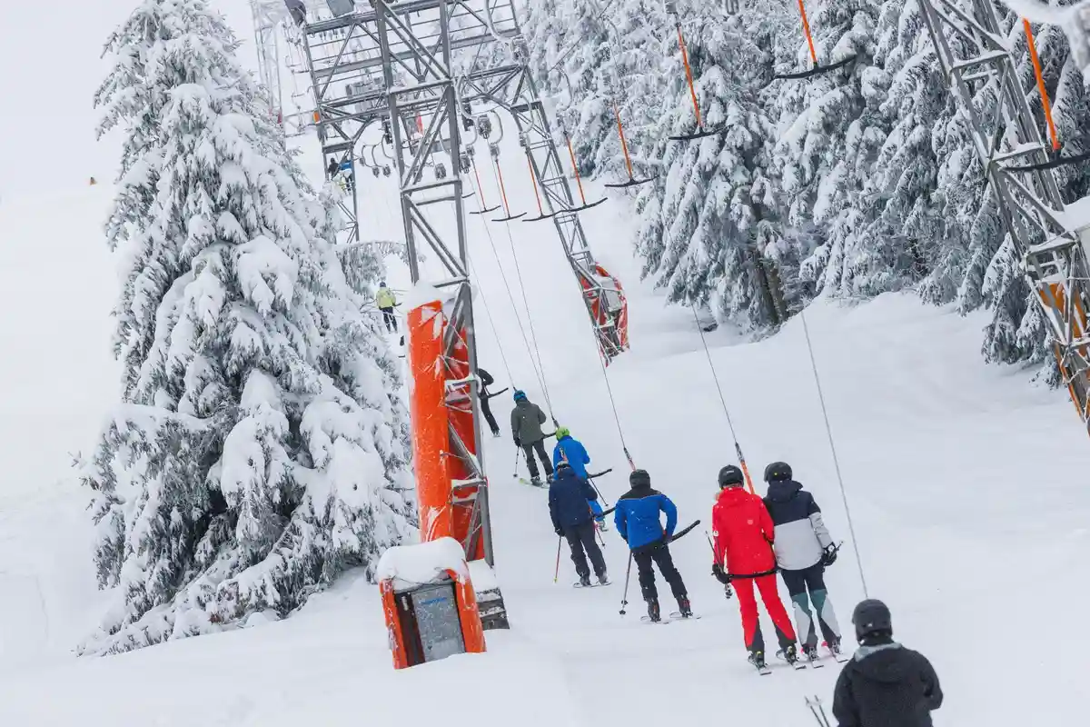 Начало лыжного сезона:Любители зимних видов спорта поднимаются по горнолыжному склону на подъемнике.