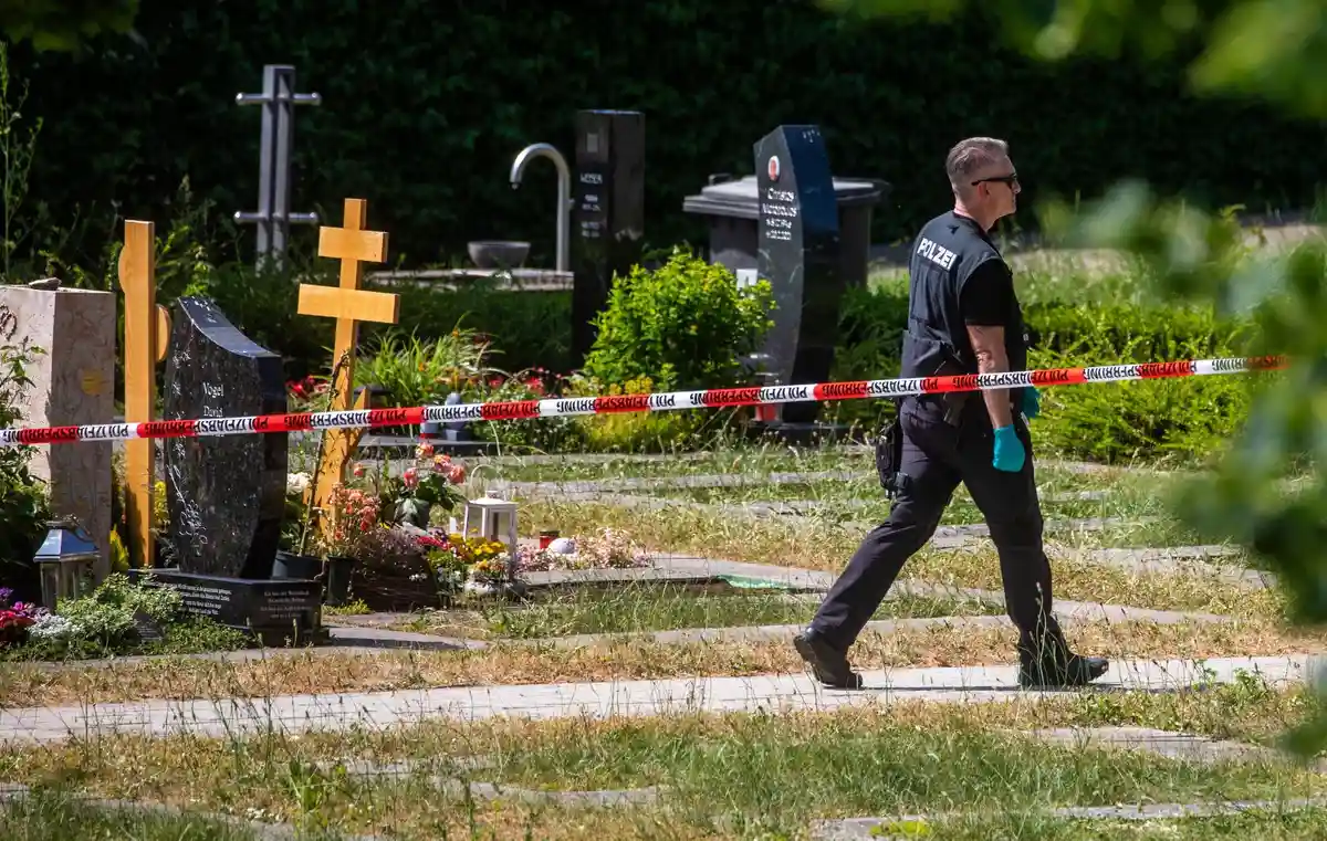Нападение на траурную общину:Полицейский идет по оцепленной части места преступления на кладбище.
