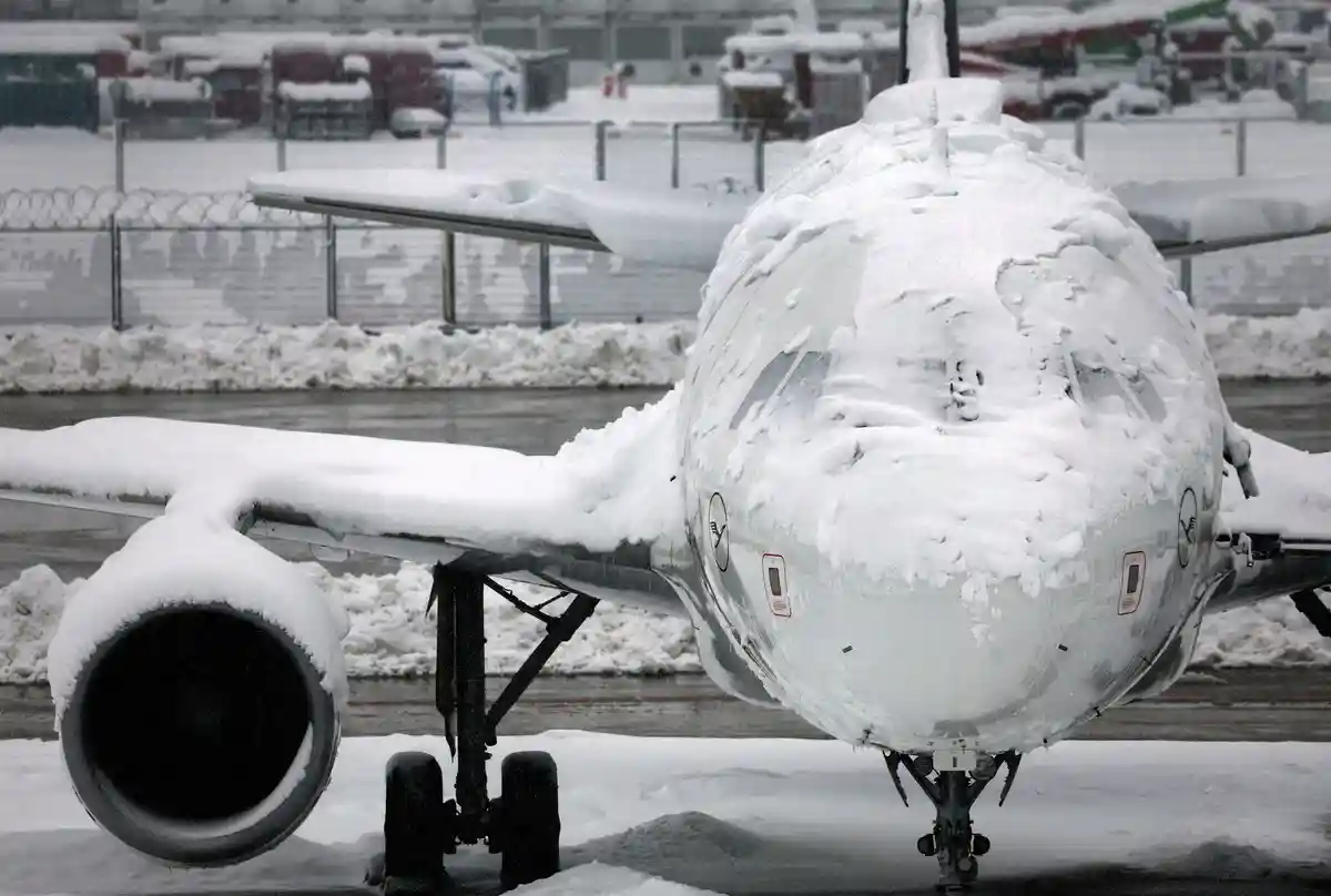 Наступление зимы на юге Германии - Мюнхен:Заснеженный самолет стоит в аэропорту.