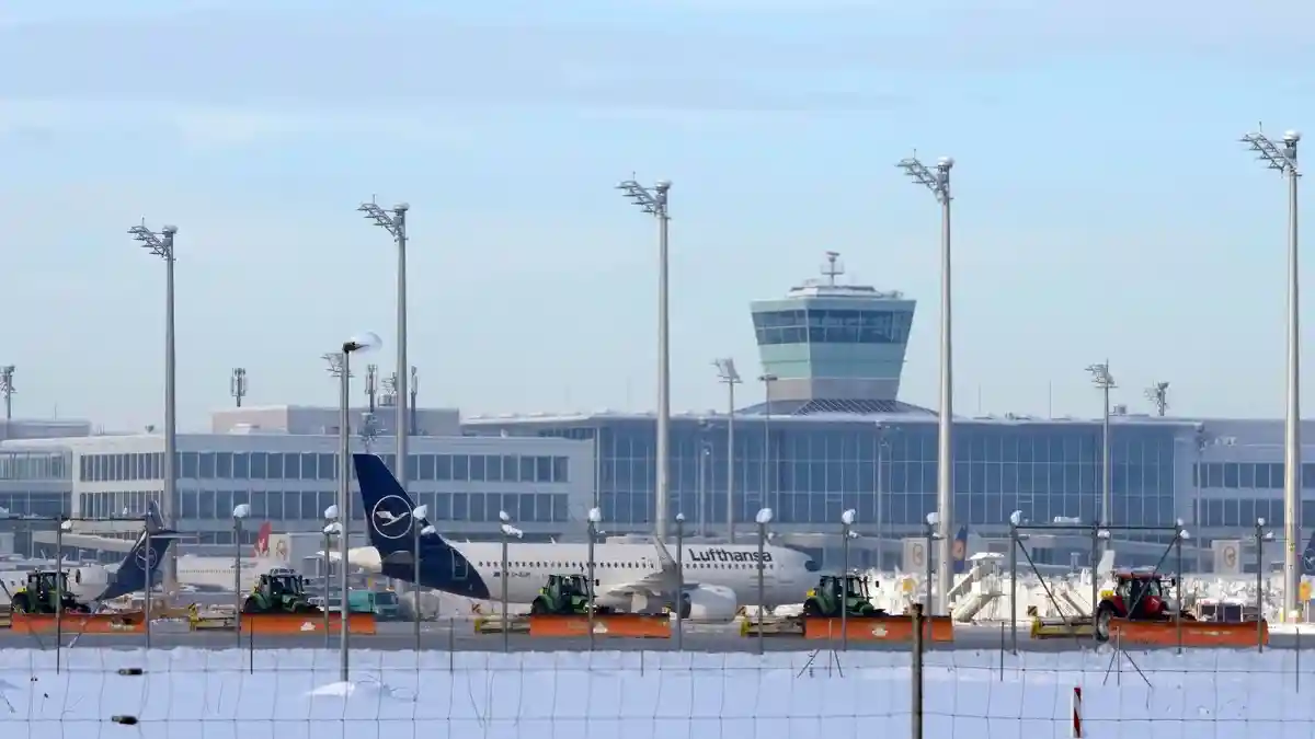 Наступление зимы на юге Германии - Мюнхен:Сотрудники аэропорта убирают снег и лед с перрона между самолетами.