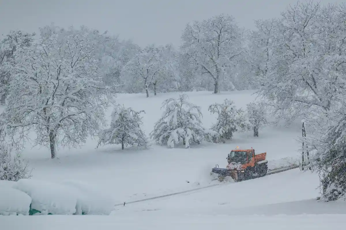 Наступление зимы в Баварском лесу:Снегоочиститель едет по заснеженному ландшафту.