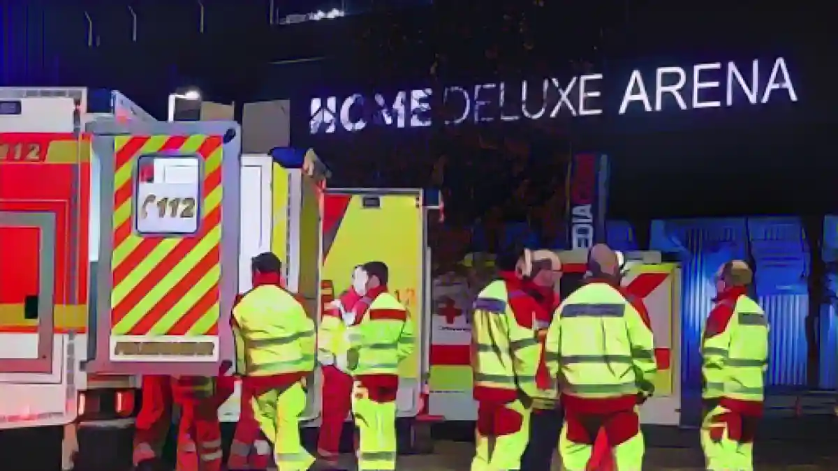 Парамедики стоят перед машинами скорой помощи у стадиона во время операции.:Парамедики стоят перед машинами скорой помощи во время операции перед стадионом. Фото