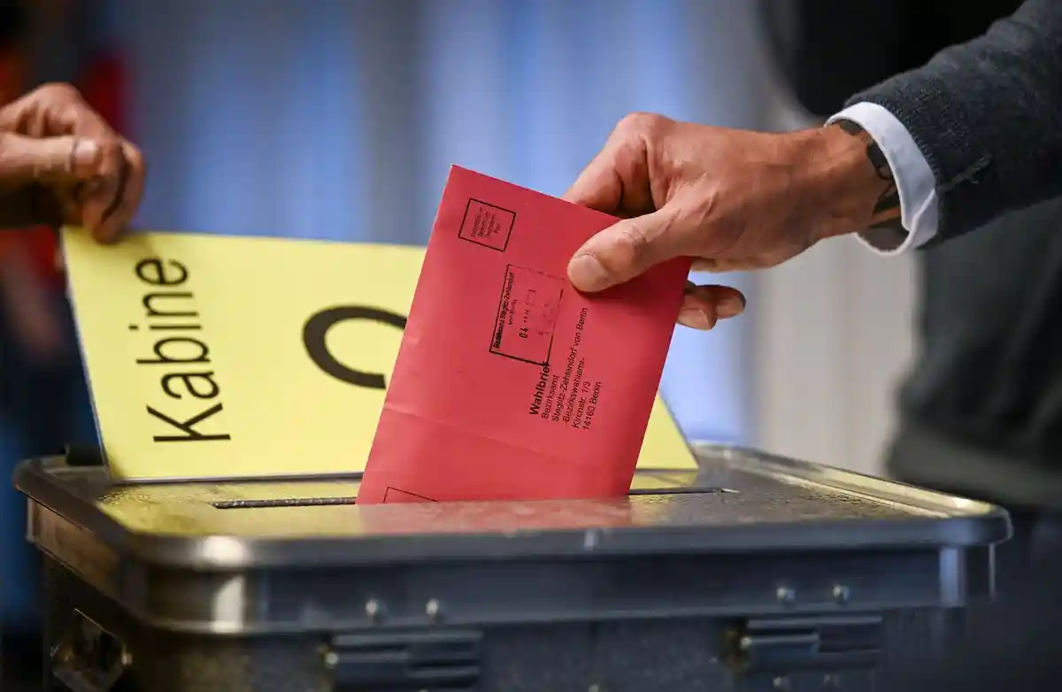 Почтовое голосование:Мужчина опускает свои бюллетени в конверте в урну для голосования.
