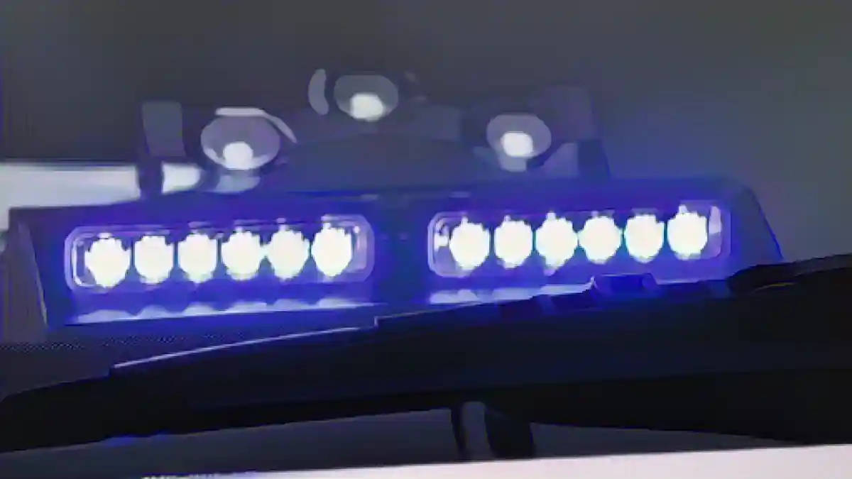 Под лобовым стеклом полицейского автомобиля светит синий фонарь.:Синий фонарь светит под лобовым стеклом полицейской машины скорой помощи. Фото