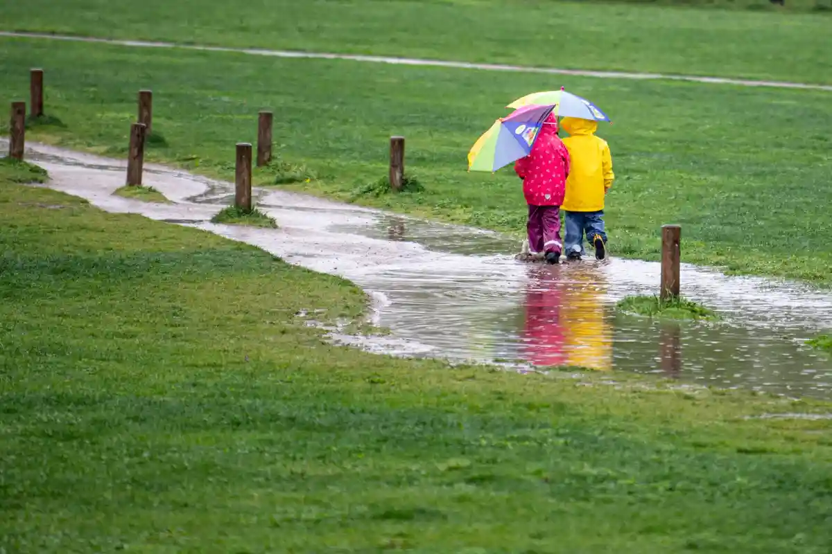 Погода в Северном Рейне-Вестфалии:Двое детей бегут по большой луже в парке.