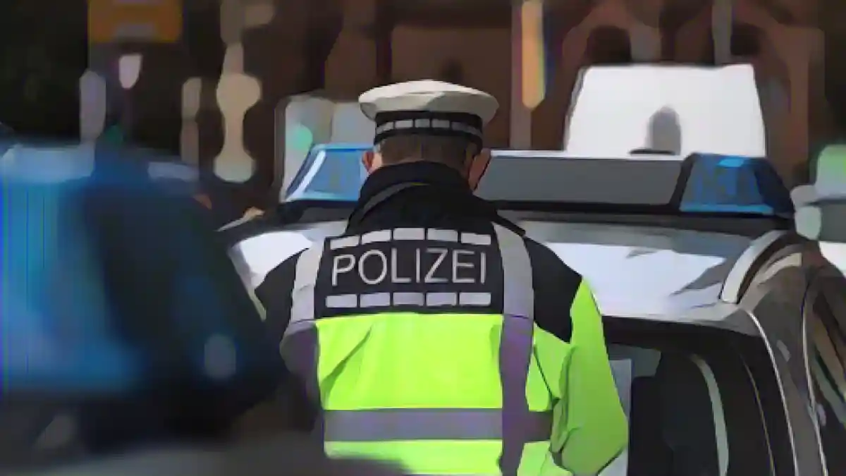 Полицейский стоит между двумя полицейскими машинами.:Полицейский стоит между двумя полицейскими машинами. Фото