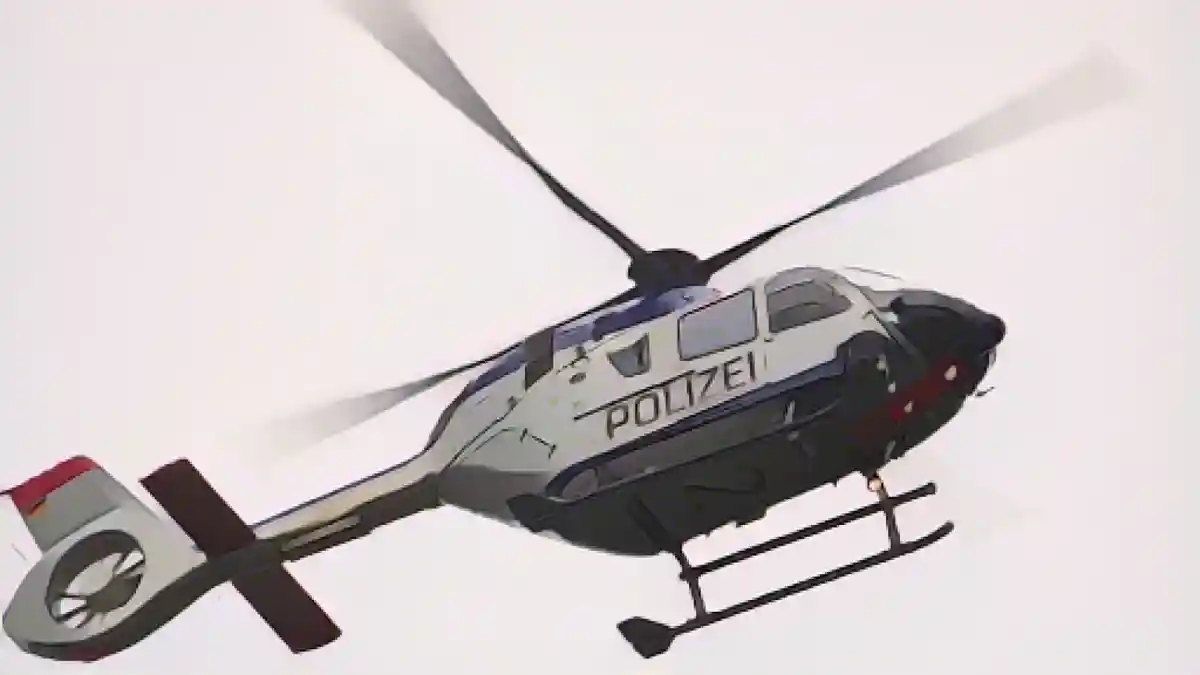 Полицейский вертолет пролетает над городом во время поисковой операции.:Полицейский вертолет пролетает над городом во время поисковой операции. Фото
