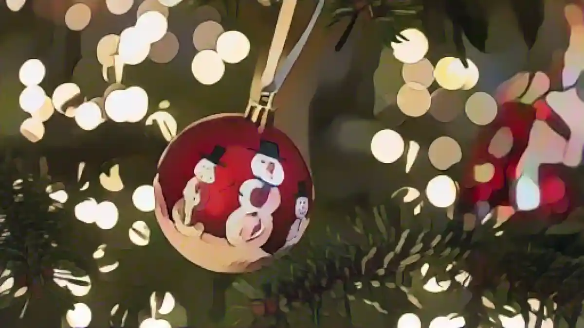 Рождественская безделушка висит на елке, украшенной гирляндами.:Рождественская безделушка свисает с елки, украшенной гирляндами. Фото