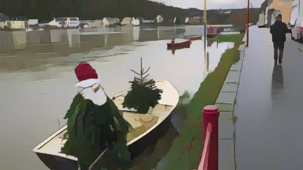 Рождественская елка, украшенная фигуркой Деда Мороза, стоит на лодке на берегу Рейна.:Рождественская елка, украшенная в виде фигуры Деда Мороза, стоит на лодке на берегу Рейна. Фото