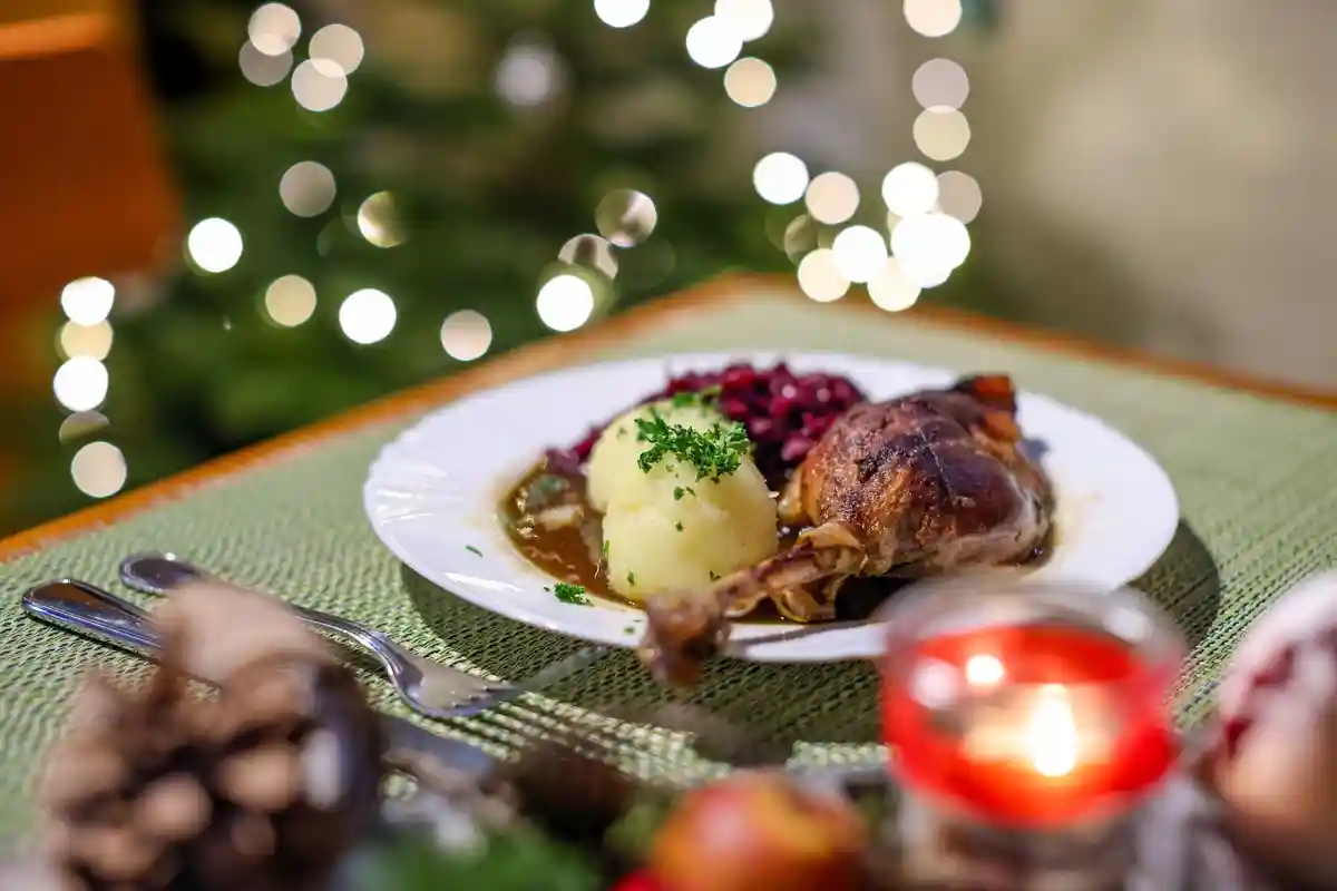 Рождественская вечеринка:На столе в ресторане стоит порция гусиной ножки с красной капустой и кнедликами.