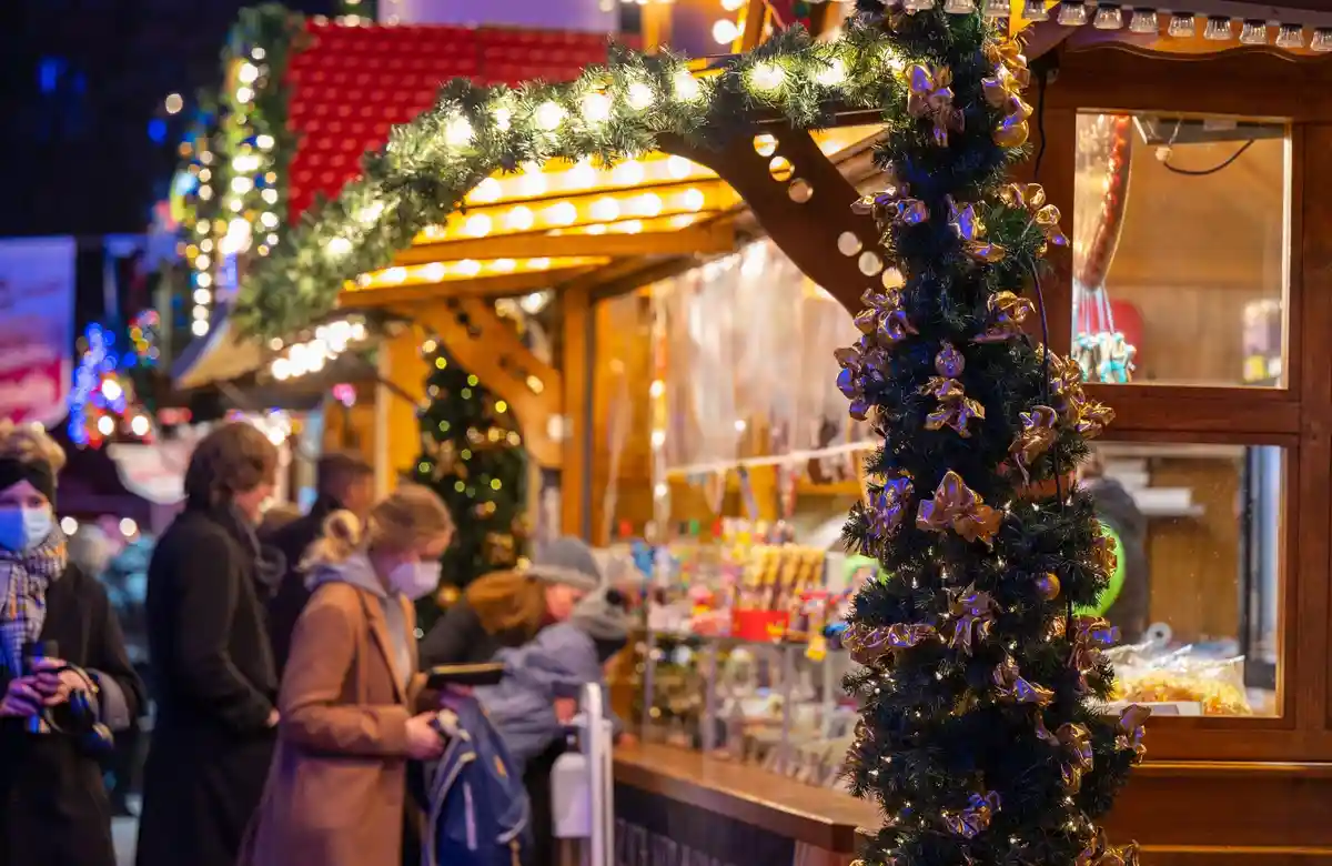 Рождественский рынок:Посетители рождественского рынка стоят у киоска со сладостями.