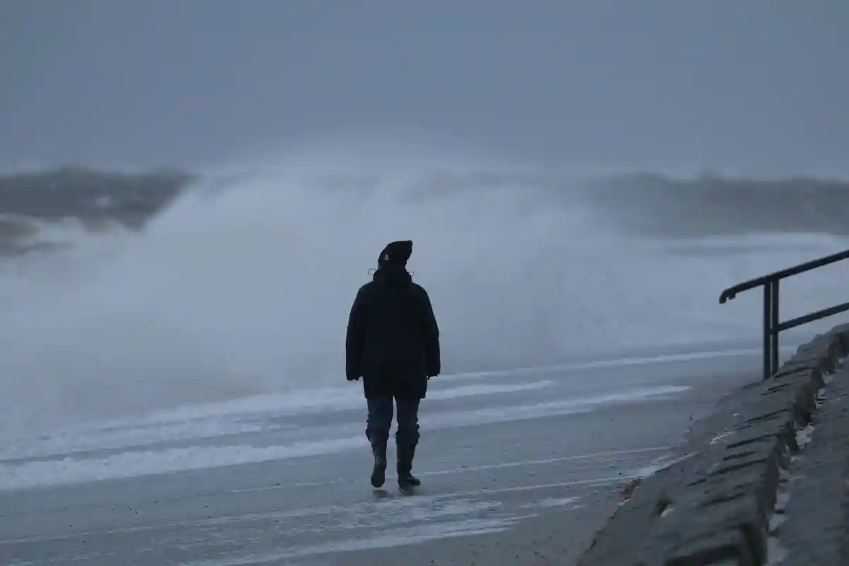 Штормовая погода на побережье Северного моря:Пешеход идет по северному пляжу восточнофризского острова Нордерни в штормовую погоду.