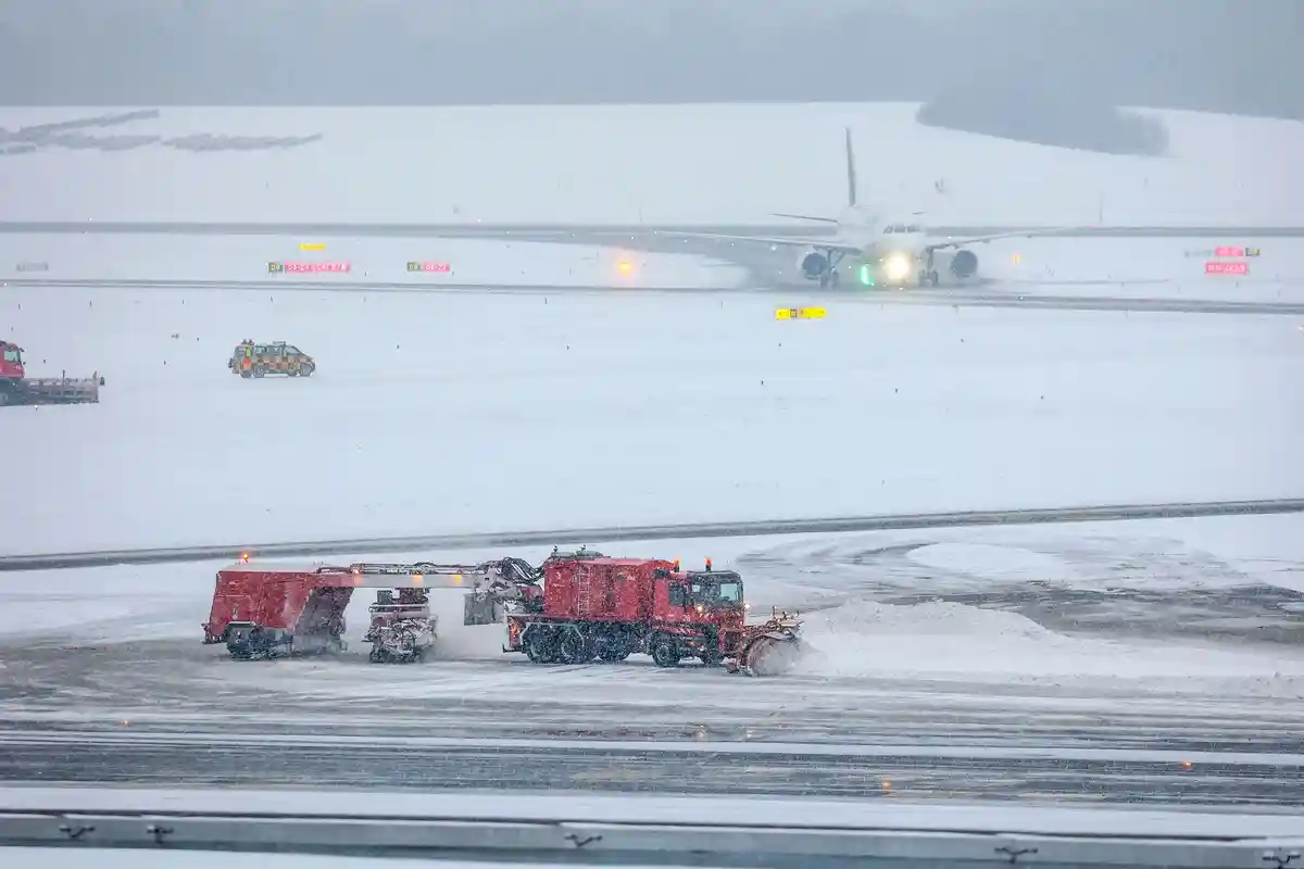 Снег в аэропорту Гамбурга:В аэропорту Гамбурга идет уборка снега. На заднем плане виден заходящий на посадку самолет авиакомпании Lufthansa.