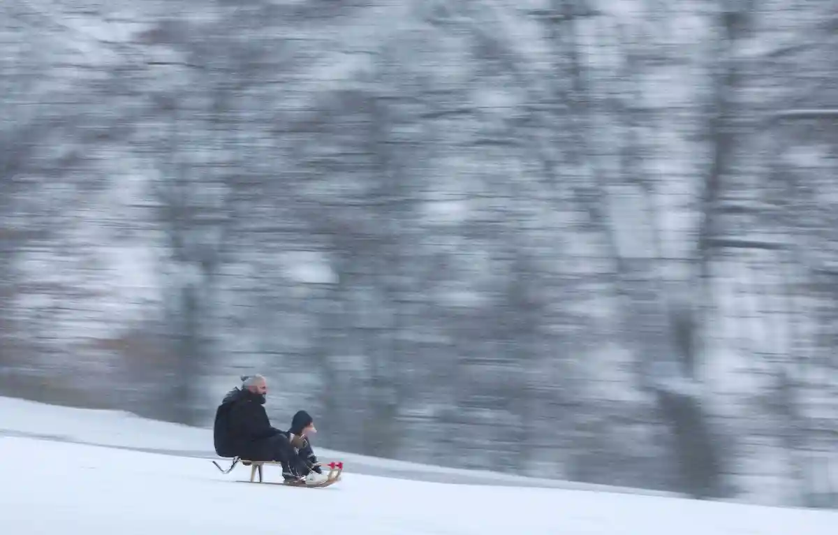 Снег в Гамбурге:Мужчина и его ребенок катаются на санках в Шанценпарке.