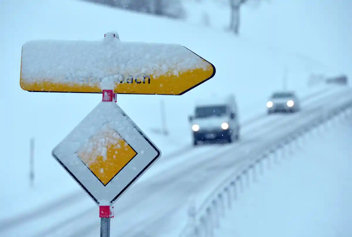 Снег:Свежий снег покрывает знак "Право на проезд" и указатель.