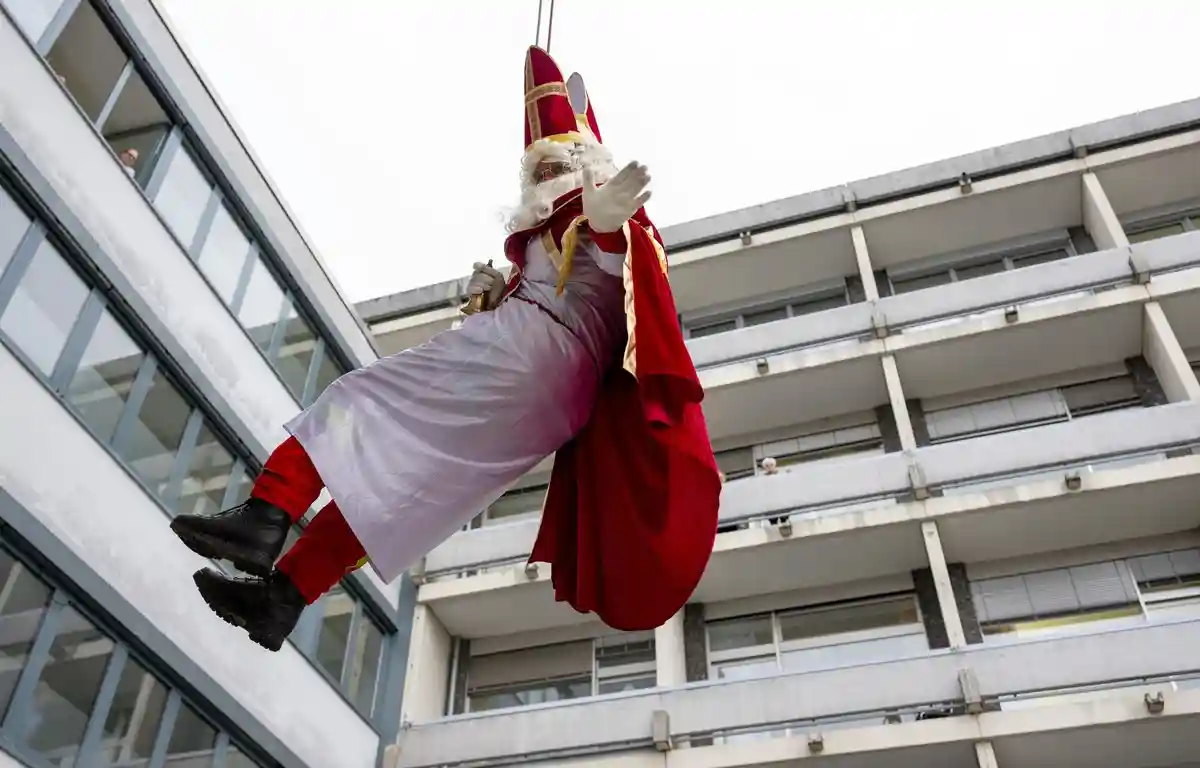 Спасатели на высоте в образе Святого Николая в Трире:Спасатель в костюме Деда Мороза спускается по стене в больнице Mutterhaus.