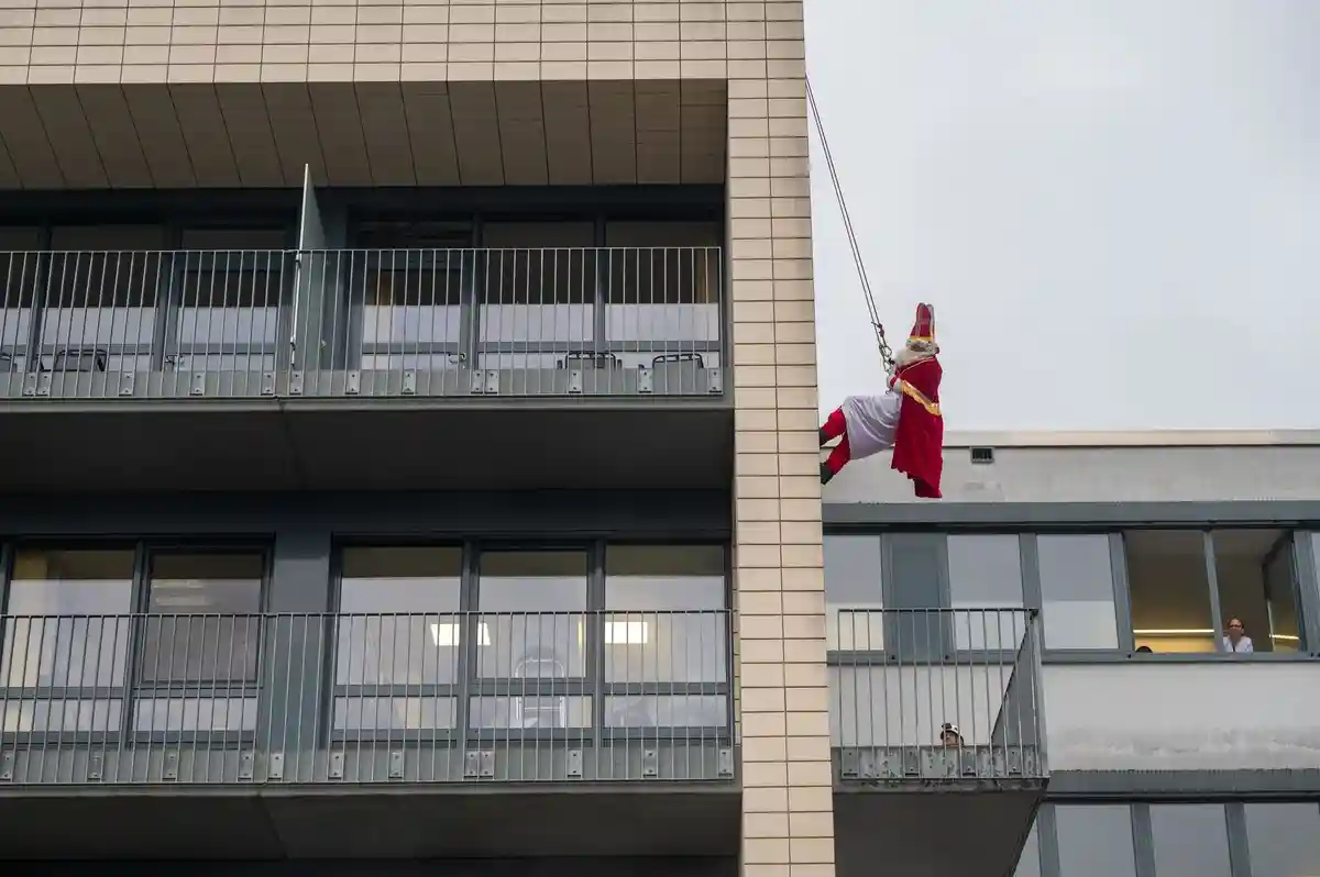 Спасатели на высоте в образе Святого Николая в Трире:Спасатель в костюме Деда Мороза спускается по стене.