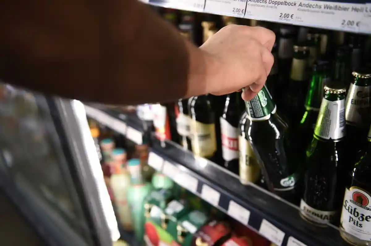 Späti:Мужчина берет бутылку пива из холодильника в ночном магазине в районе Берлин-Митте.