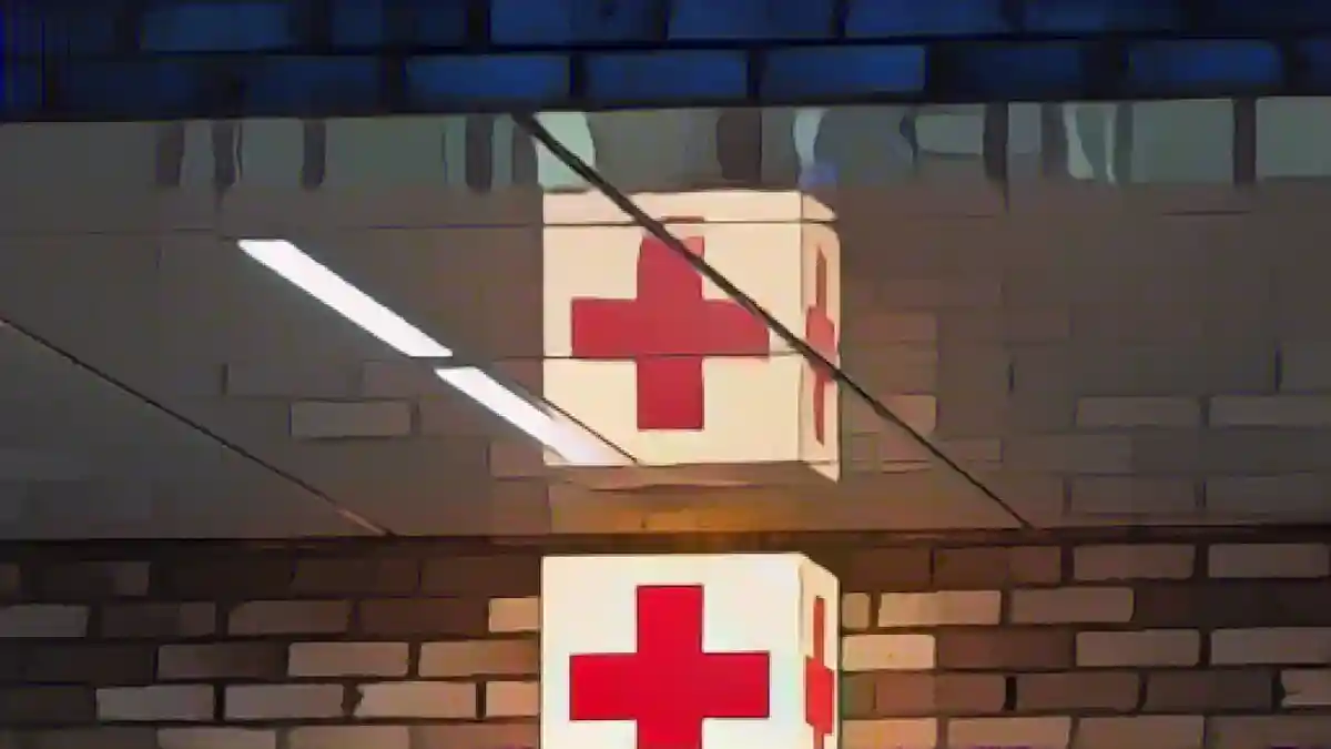 Световой короб с красным крестом висит у здания отделения неотложной помощи больницы.:Световой короб с красным крестом висит у отделения неотложной помощи одной из больниц. Фото