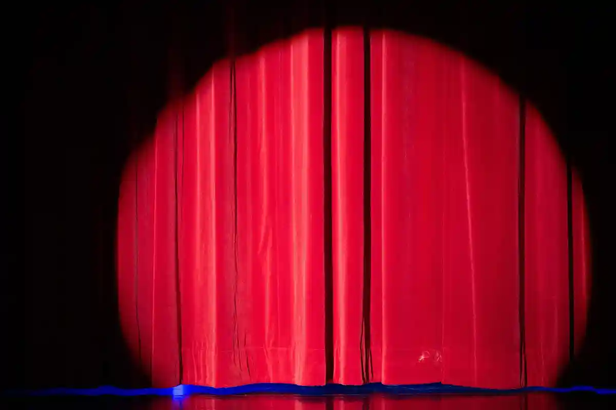 Театральная сцена:Прожектор освещает занавес на сцене.