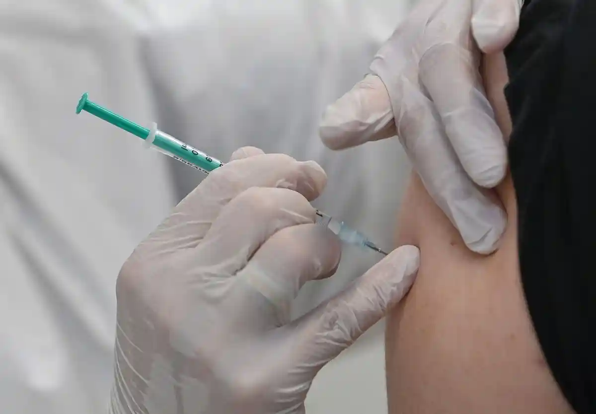 Вакцинация против короны:Сотрудник центра вакцинации прививает мужчину от коронавируса.