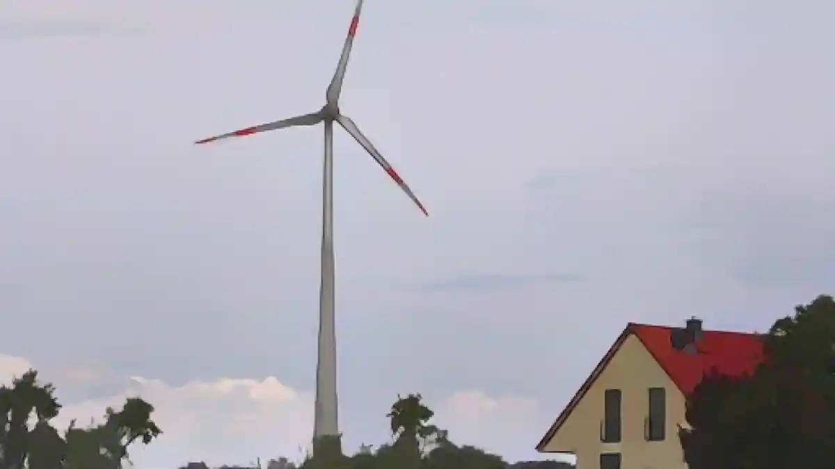 Ветряная турбина вращается на ветру за жилым домом.:Ветряная турбина вращается на ветру за жилым домом. Фото