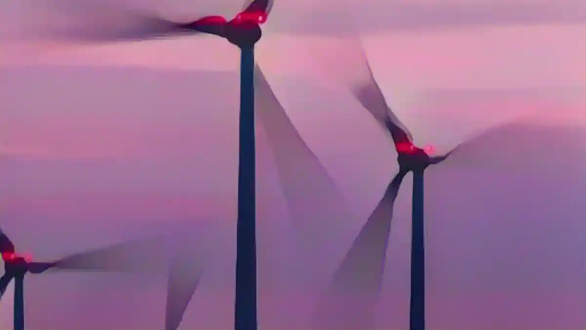 Ветряные турбины, освещенные сигнальными лампами, вращаются после захода солнца.:Ветряные турбины, подсвеченные сигнальными лампами, поворачиваются после захода солнца. Фото