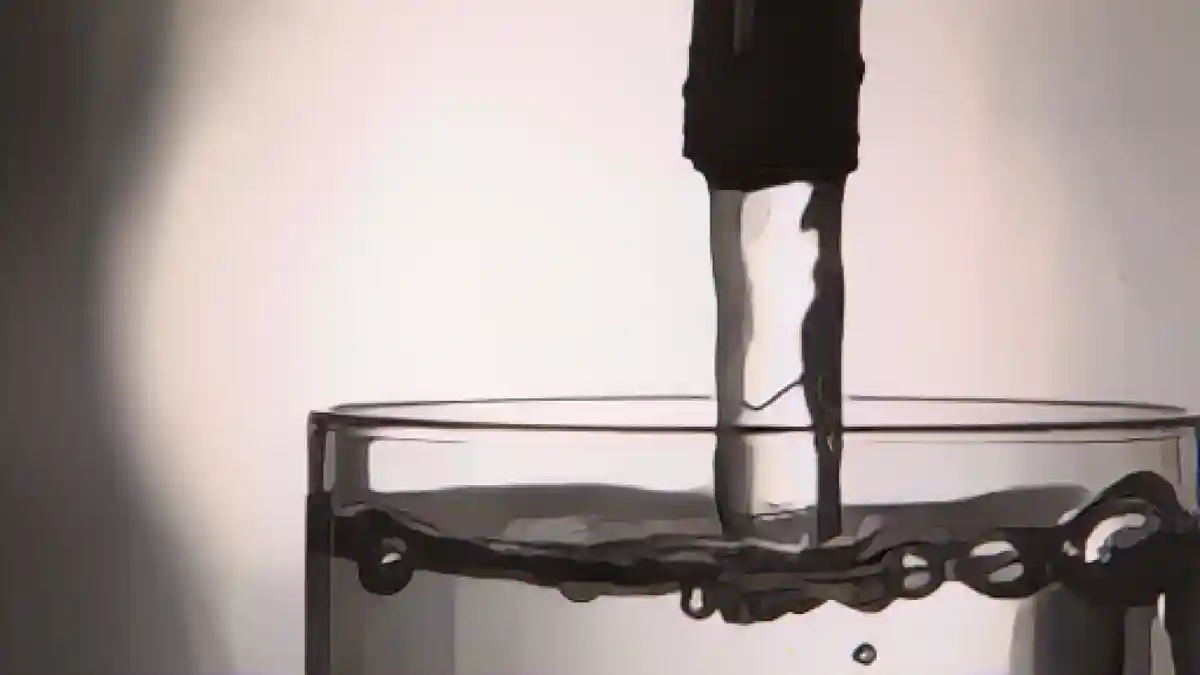Вода из крана течет в стакан.:Водопроводная вода течет из крана в стакан. Фото