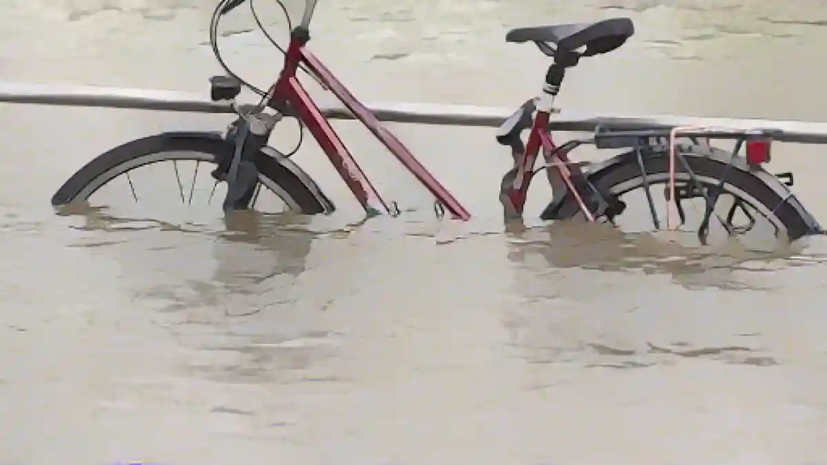 Высокая вода Эльбы огибает велосипед на берегу террасы.:Высокая вода в Эльбе окружает велосипед на берегу террасы. Фото