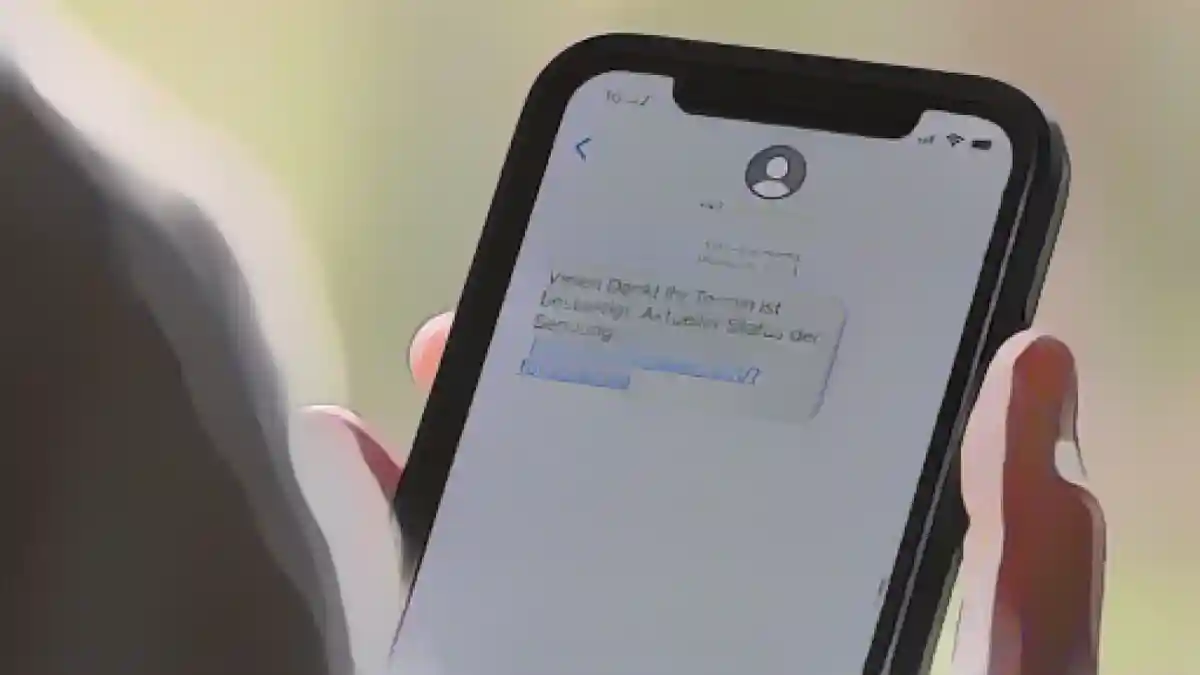 Женщина держит в руках смартфон, на дисплее которого отображается мошенническое текстовое сообщение.:Женщина держит смартфон с мошенническим текстовым сообщением на дисплее. Фото