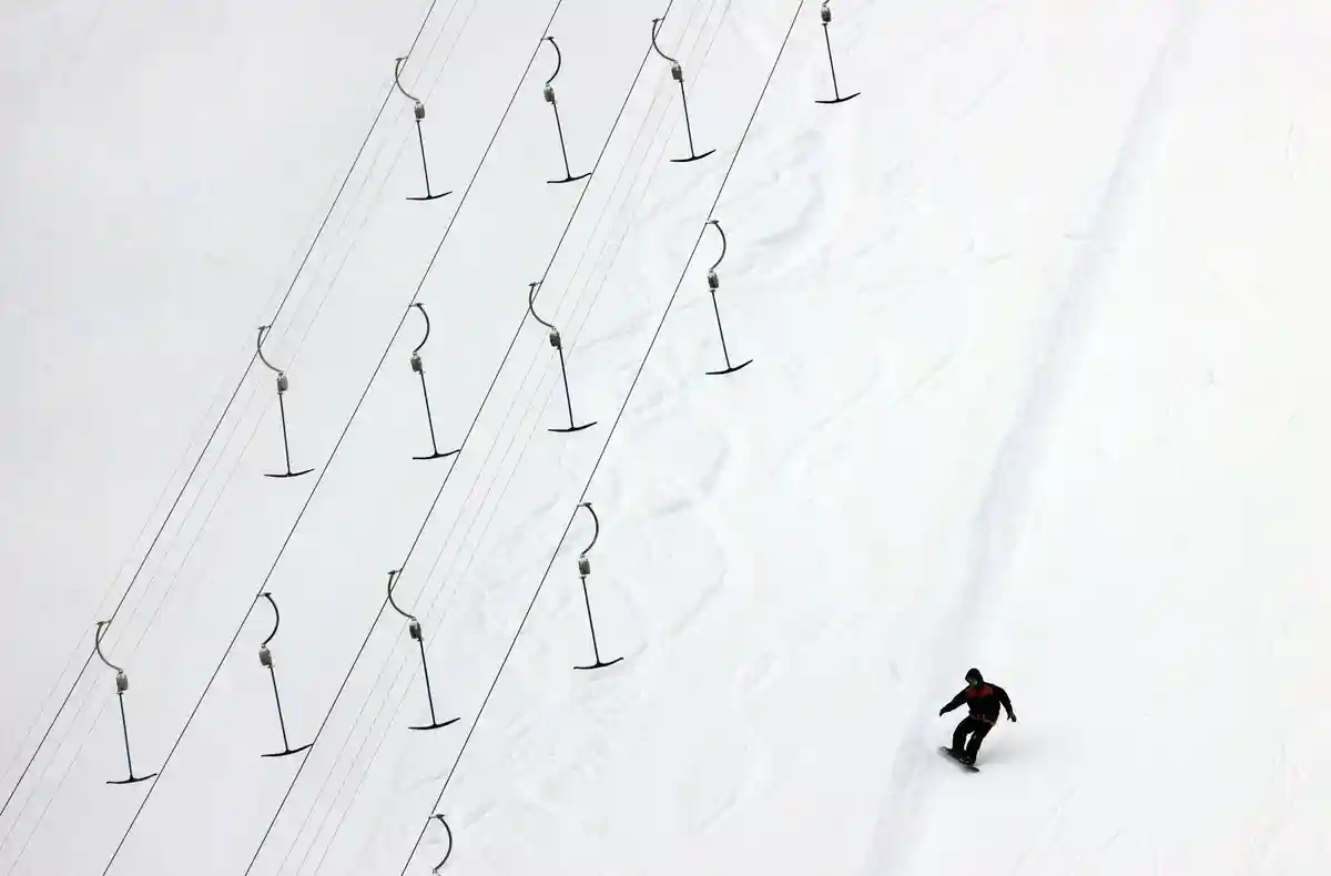 Зима:Сноубордист спускается по трассе.