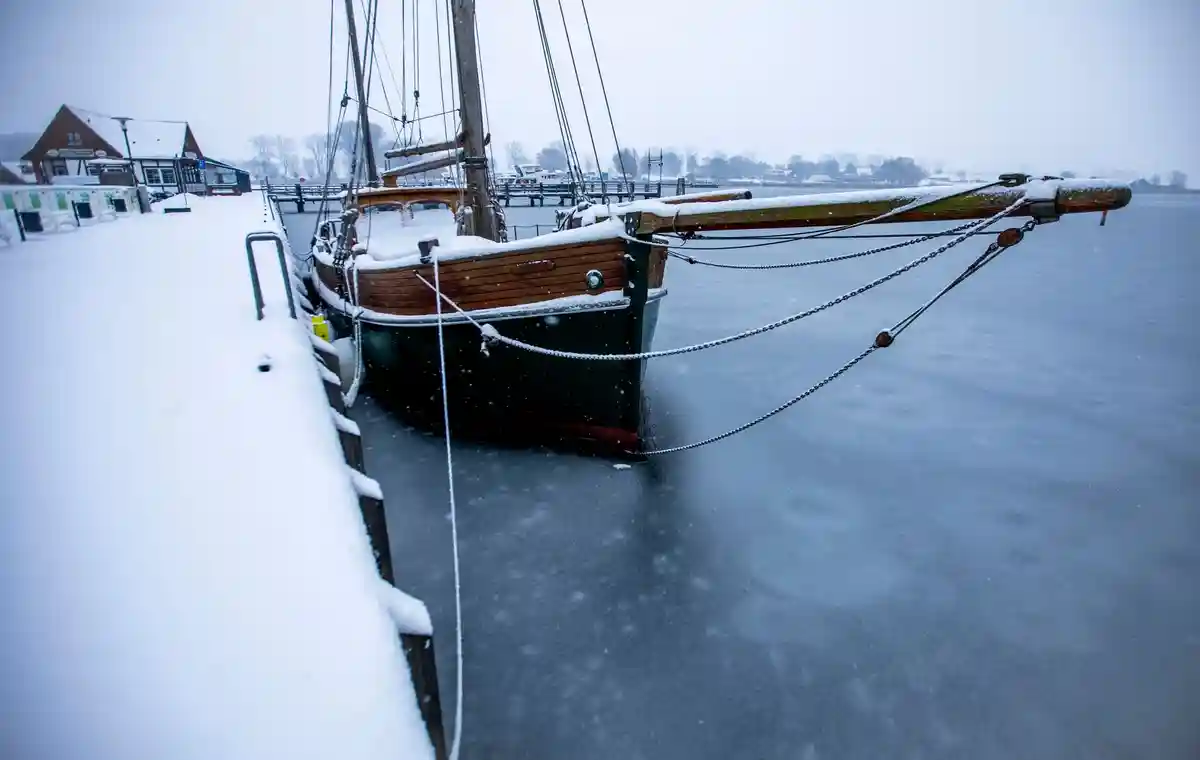 Зимняя погода на севере Германии:Парусник, покрытый снегом, вмерз в лед в гавани на острове Поэль в Балтийском море.