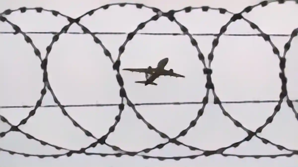 Самолет взлетает - снимок сделан через колючую проволоку на ограждении аэропорта.:Самолет взлетает - фото через колючую проволоку на ограждении аэропорта. Фото